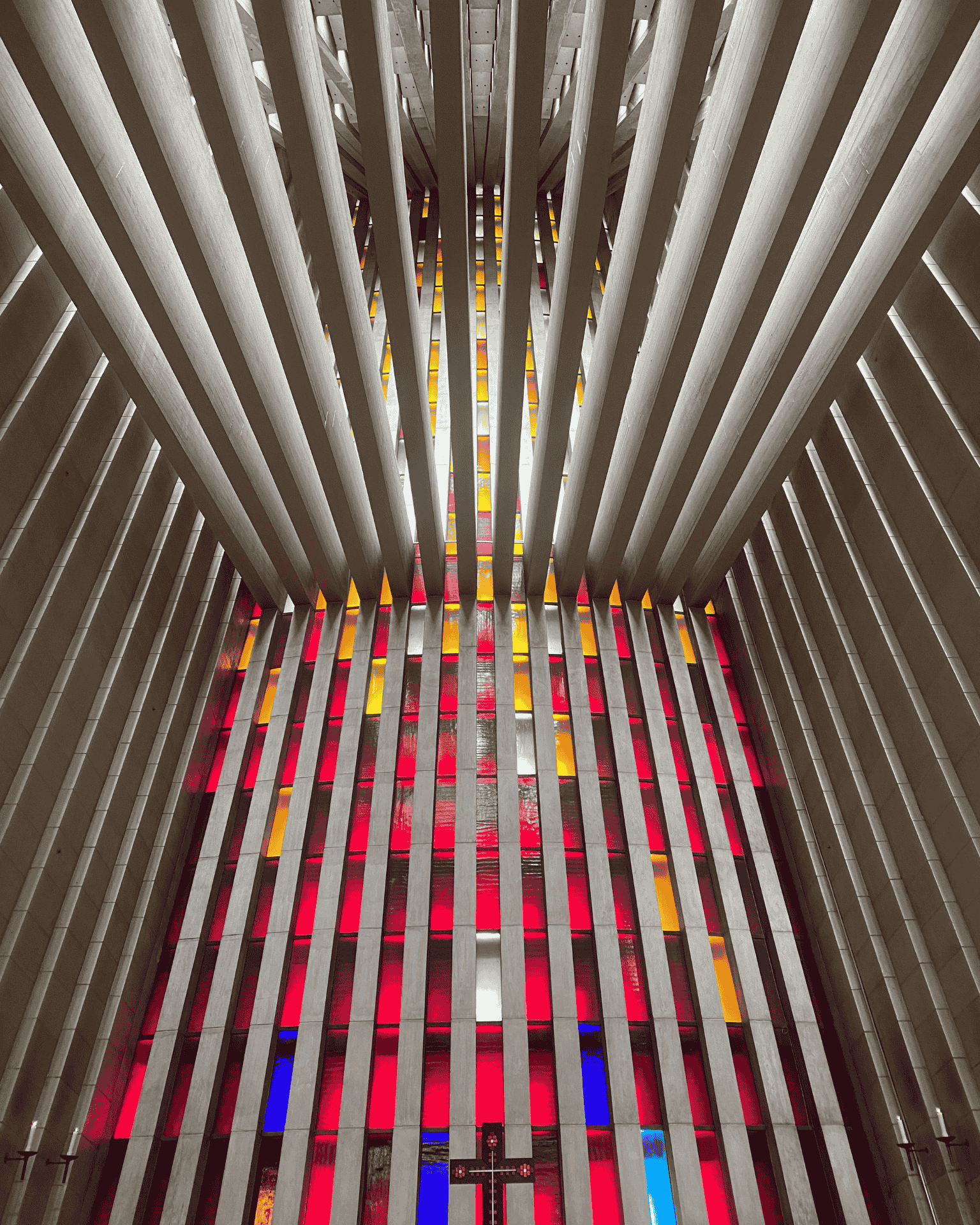 Veggen bak altertavla i Kirkelandet kirke. Glasskunst i større deler med farger fra blå nederst til gul øverst