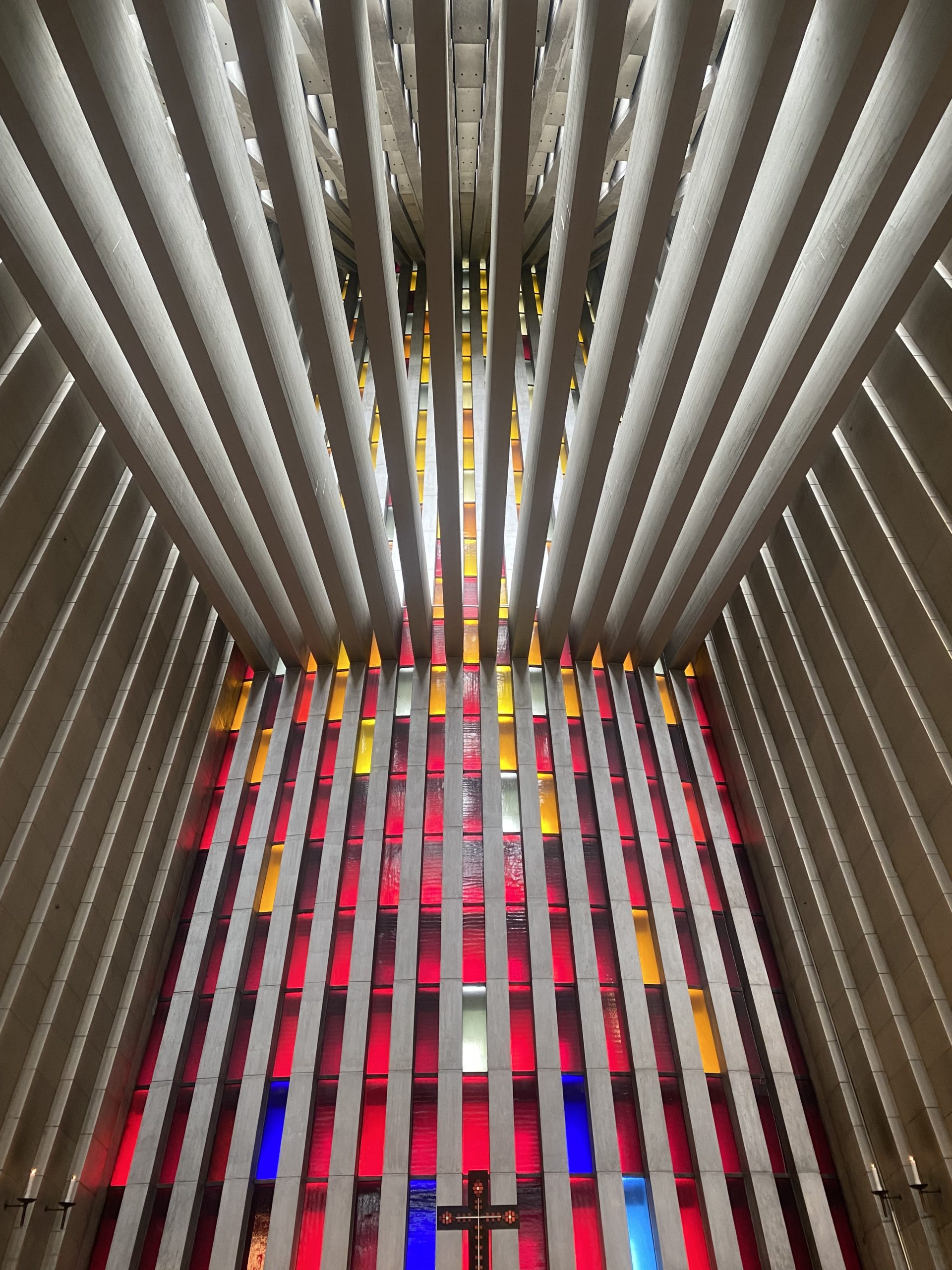 Veggen bak altertavla i Kirkelandet kirke. Glasskunst i større deler med farger fra blå nederst til gul øverst